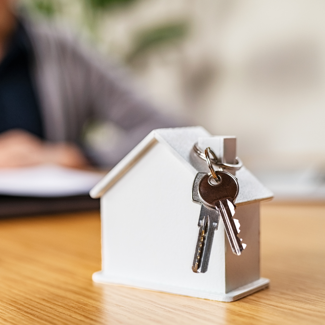 Image of a small white house with keys hanging from the chimney, symbolizing homeownership and entry into the housing market.