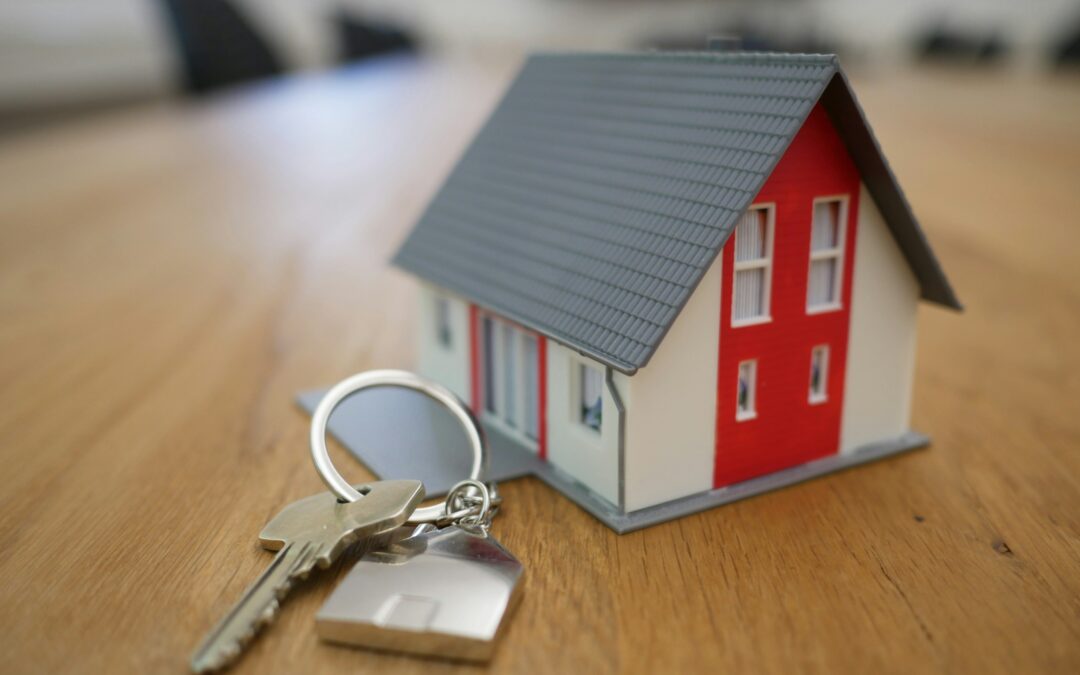 image of a miniature house with a key, representing the real estate housing market
